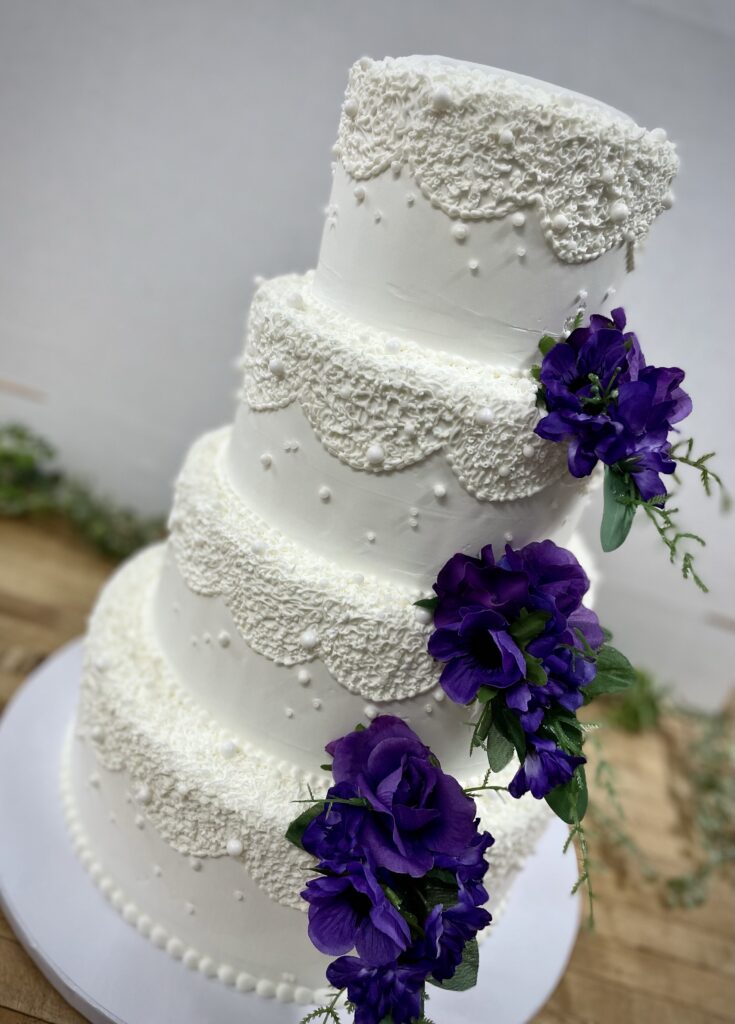 Two layer white cake with dark colored flowers